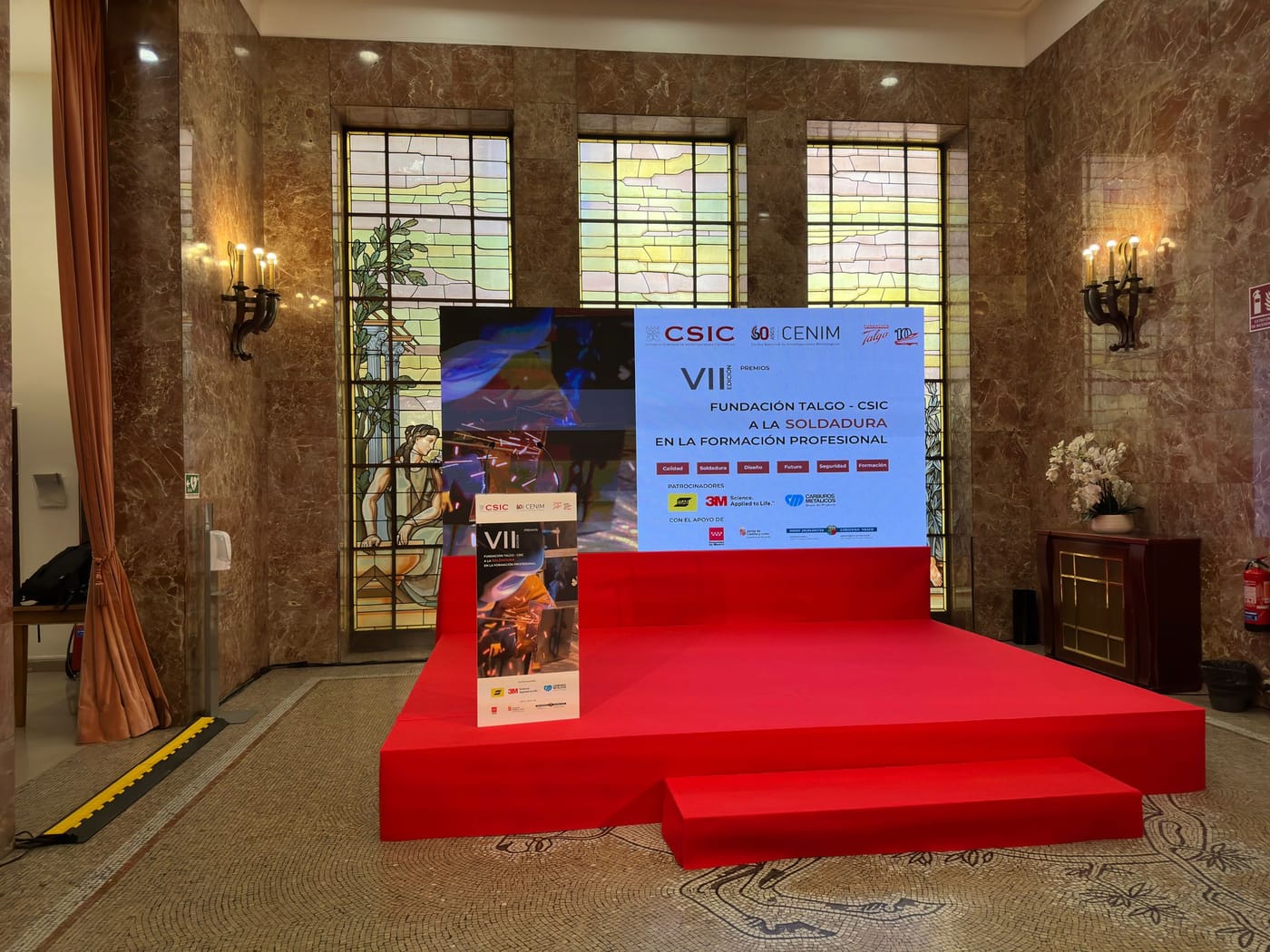 Pantalla LED montada como fondo del escenario de un salón de actos, con la gráfica de una entrega de premios