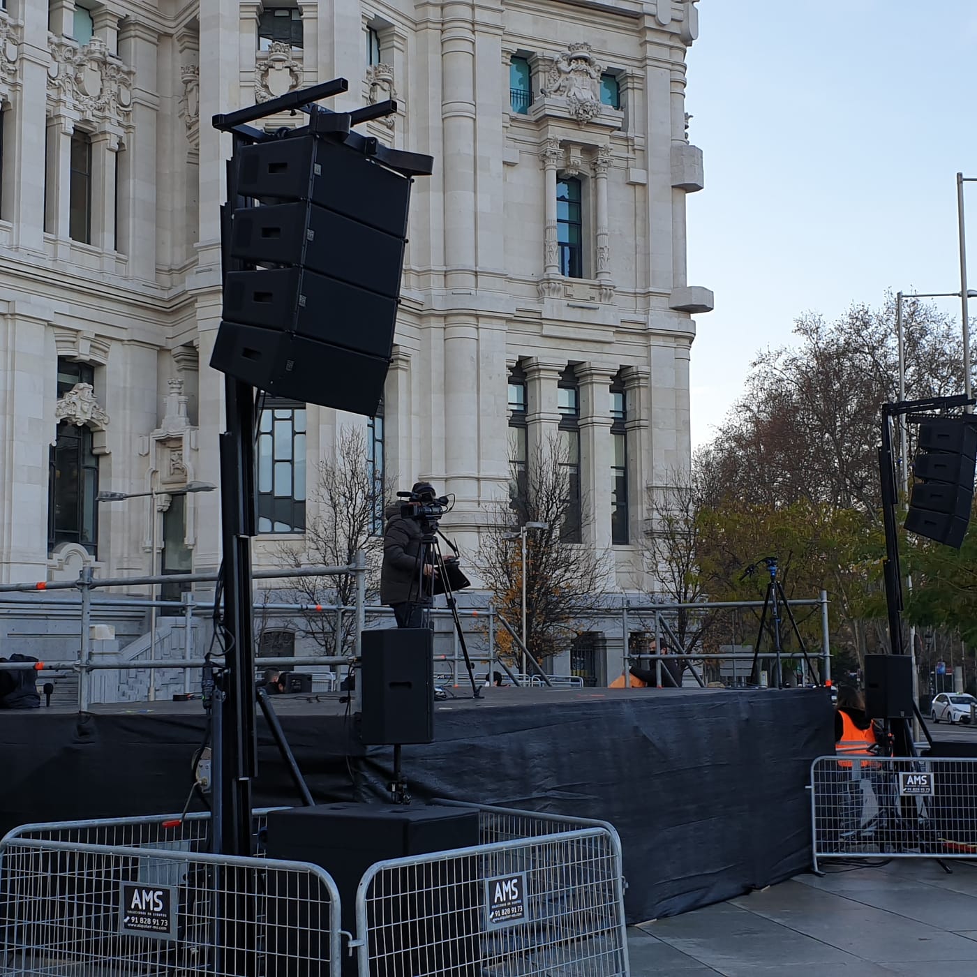 Columna de line array elevada sobre una torre junto a un escenario, en un evento al aire libre en Madrid